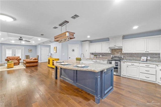 23807 Stuart Place Rd, Harlingen, TX 78552 - kitchen with stainless steel electric range oven, white cabinets, dark wood-type flooring, under cabinet range hood, and a breakfast bar