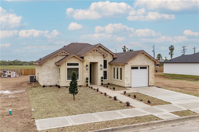 view of front of home with concrete driveway, stone siding, roof with shingles, an attached garage, and central AC