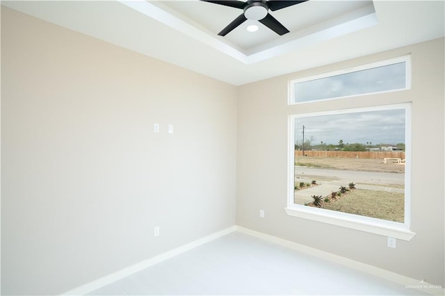 empty room with baseboards, a raised ceiling, and a ceiling fan