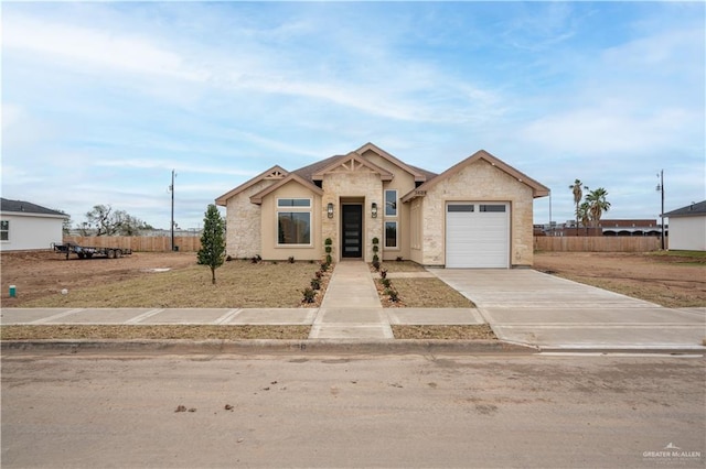 view of front facade featuring an attached garage, stone siding, driveway, and fence