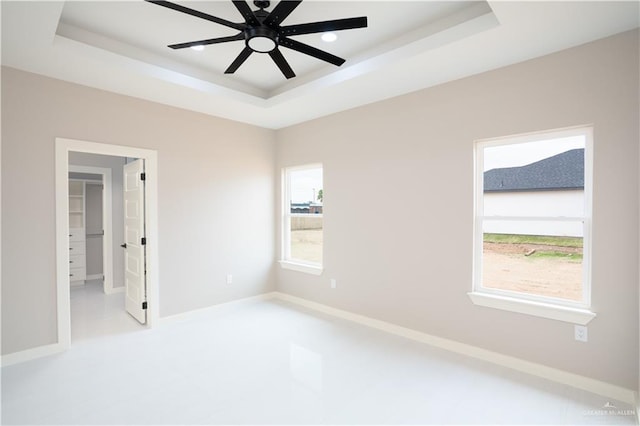 spare room featuring baseboards, a tray ceiling, and ceiling fan