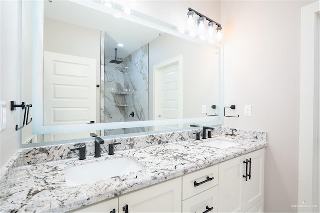 bathroom featuring double vanity, a sink, and a marble finish shower