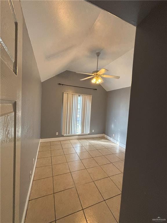 unfurnished room featuring ceiling fan, light tile patterned floors, and vaulted ceiling