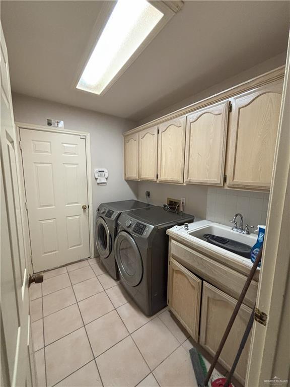 laundry area featuring washer and clothes dryer, light tile patterned flooring, cabinets, and sink