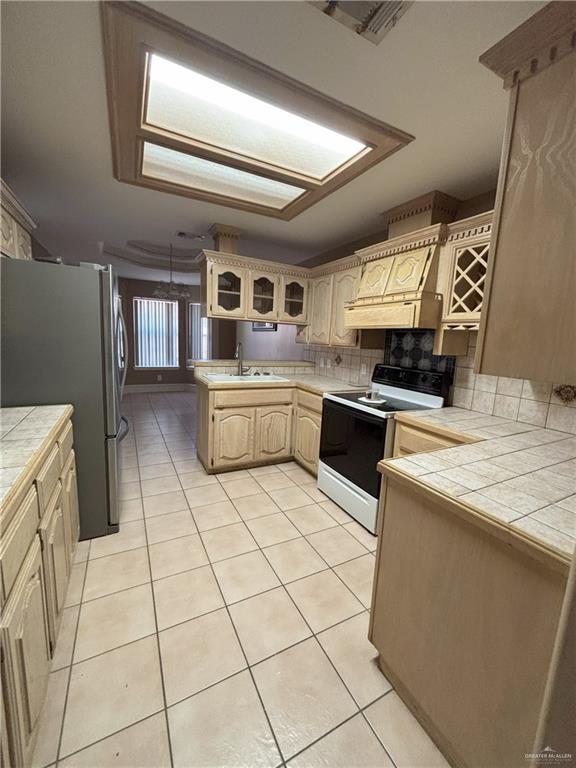 kitchen with stainless steel fridge, backsplash, white electric range oven, light tile patterned floors, and tile countertops