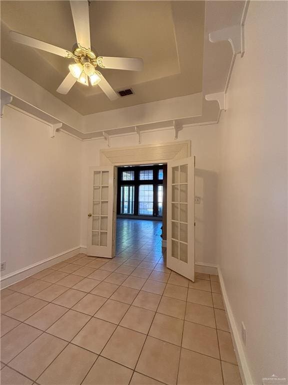 tiled spare room with a raised ceiling, ceiling fan, and french doors