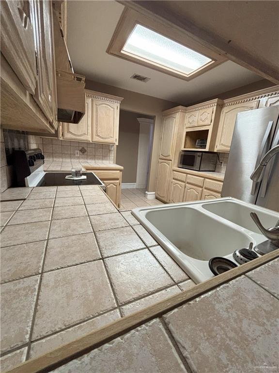 kitchen with decorative backsplash, appliances with stainless steel finishes, tile counters, and exhaust hood