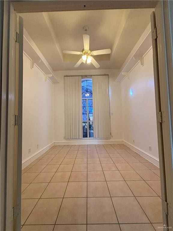 unfurnished room with a tray ceiling, ceiling fan, and light tile patterned floors