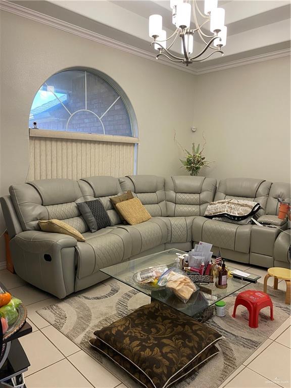 4907 N 25th Ln, Mcallen, TX 78504 - living room with crown molding, a chandelier, tile patterned floors, and a raised ceiling