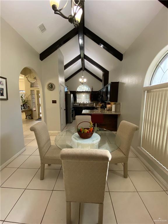 4907 N 25th Ln, Mcallen, TX 78504 - dining area with light tile patterned flooring, vaulted ceiling with beams, arched walkways, an inviting chandelier, and visible vents