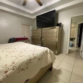 4907 N 25th Ln, Mcallen, TX 78504 - bedroom with ceiling fan, light tile patterned flooring, and a tray ceiling