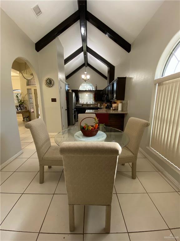 4907 N 25th Ln, Mcallen, TX 78504 - dining space with a chandelier, vaulted ceiling with beams, light tile patterned floors, arched walkways, and visible vents