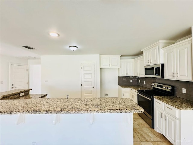 606 S Paseo Del Rey St, Mission, TX 78572 - kitchen featuring stainless steel appliances, a kitchen breakfast bar, tasteful backsplash, and light stone counters