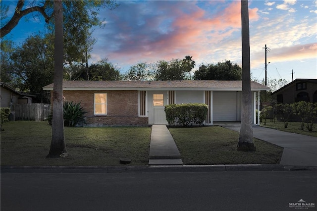 ranch-style house featuring brick siding, a yard, concrete driveway, fence, and a garage