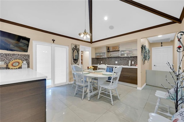 dining space with light tile patterned flooring, vaulted ceiling, ornamental molding, and baseboards