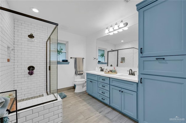 full bathroom with a shower stall, double vanity, wood finished floors, and toilet
