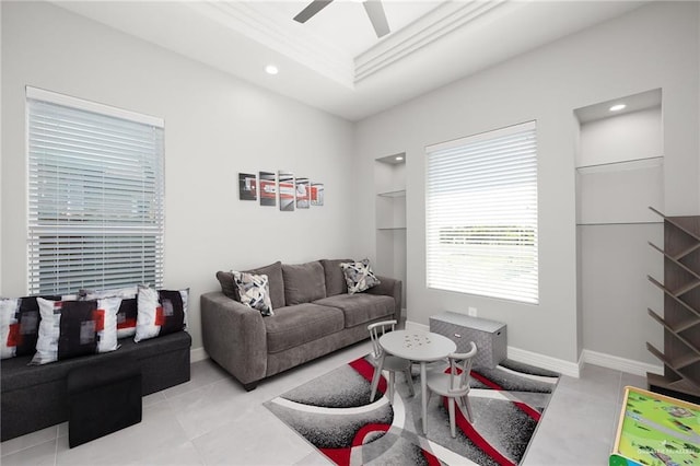 tiled living room with ceiling fan, a raised ceiling, and crown molding