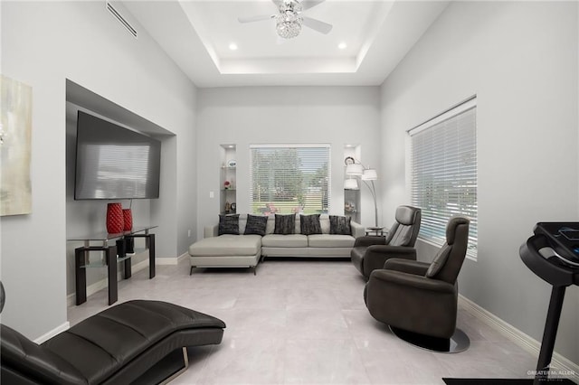 living room featuring ceiling fan, a healthy amount of sunlight, and a raised ceiling