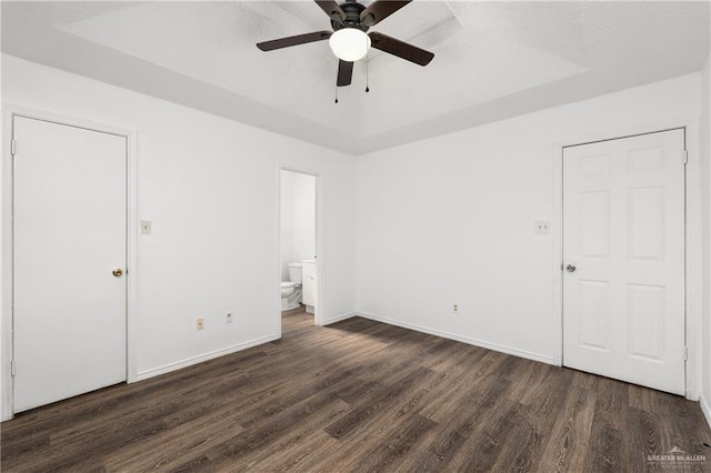 20538 Rio Rancho Rd, Harlingen, TX 78552 - unfurnished bedroom with dark wood-style floors, a tray ceiling, ensuite bathroom, and a ceiling fan