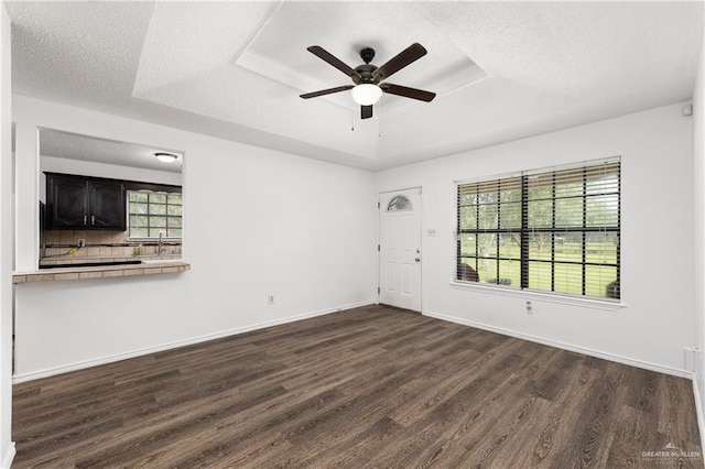 20538 Rio Rancho Rd, Harlingen, TX 78552 - unfurnished living room featuring a raised ceiling, dark wood-style flooring, ceiling fan, and a textured ceiling