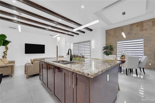 3408 Madison Ave, Edinburg, TX 78539 - kitchen with open floor plan, decorative light fixtures, light stone countertops, dark brown cabinetry, and a kitchen island with sink