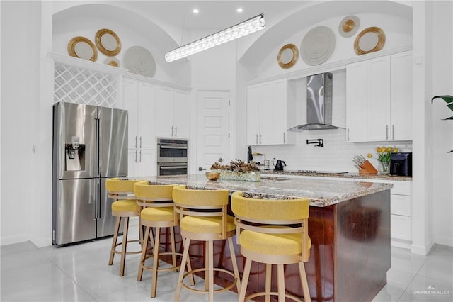 3408 Madison Ave, Edinburg, TX 78539 - kitchen featuring appliances with stainless steel finishes, wall chimney exhaust hood, light tile patterned floors, backsplash, and white cabinetry