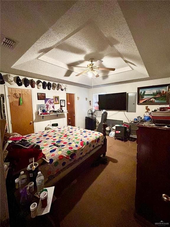 carpeted bedroom with a textured ceiling, a raised ceiling, and ceiling fan