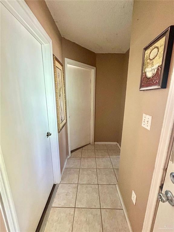 corridor with light tile patterned floors and a textured ceiling