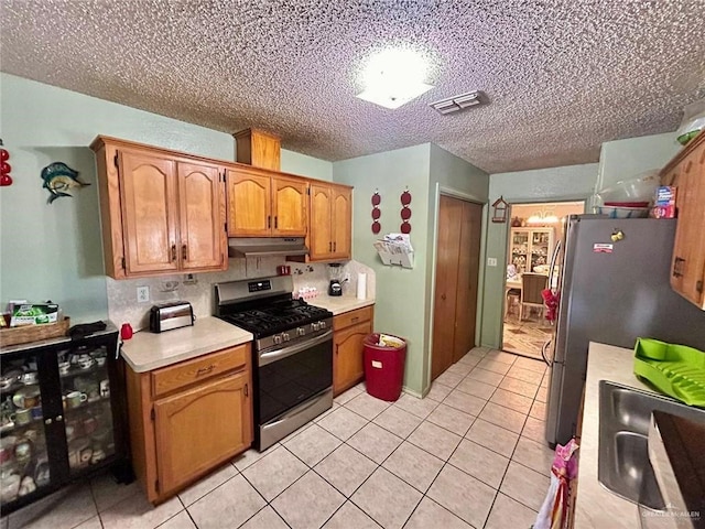 kitchen featuring light tile patterned floors, a textured ceiling, stainless steel appliances, and sink