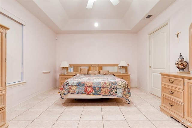 tiled bedroom featuring ceiling fan and a tray ceiling