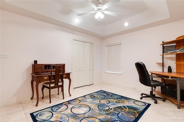 tiled home office featuring a raised ceiling and ceiling fan