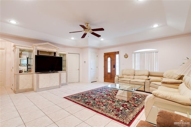 living room featuring light tile patterned floors, a tray ceiling, and ceiling fan