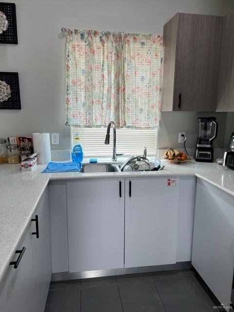 kitchen featuring dark tile patterned floors, white cabinets, and sink