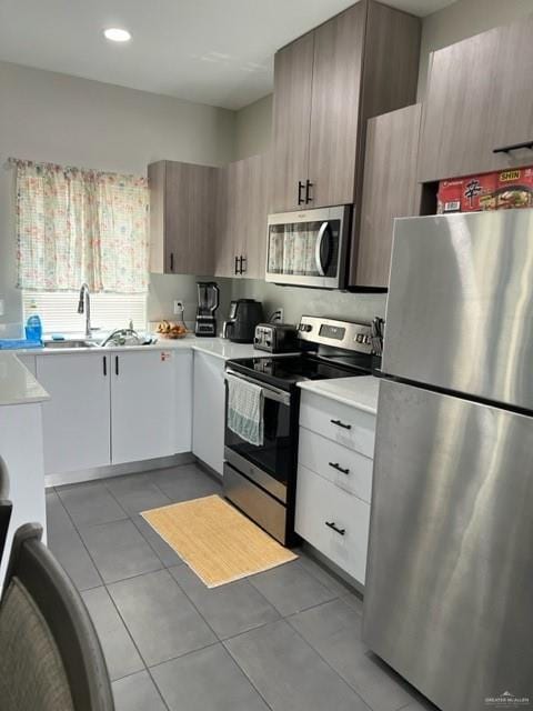 kitchen with white cabinets, sink, light tile patterned floors, and stainless steel appliances