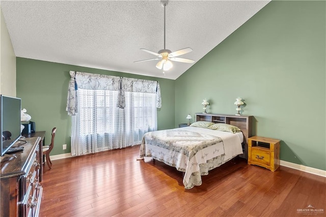 bedroom featuring lofted ceiling, a textured ceiling, baseboards, and wood finished floors