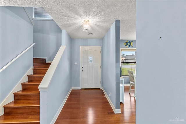 entryway featuring visible vents, baseboards, dark wood finished floors, stairway, and a textured ceiling