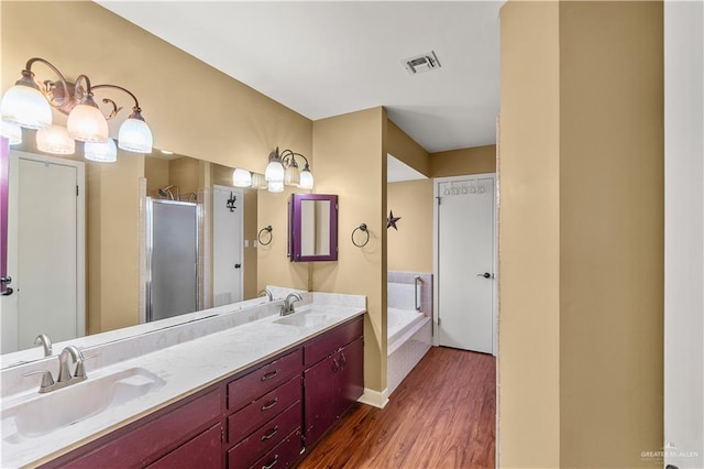 full bathroom with a shower stall, visible vents, a sink, and wood finished floors