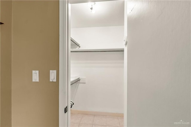 walk in closet with light tile patterned floors