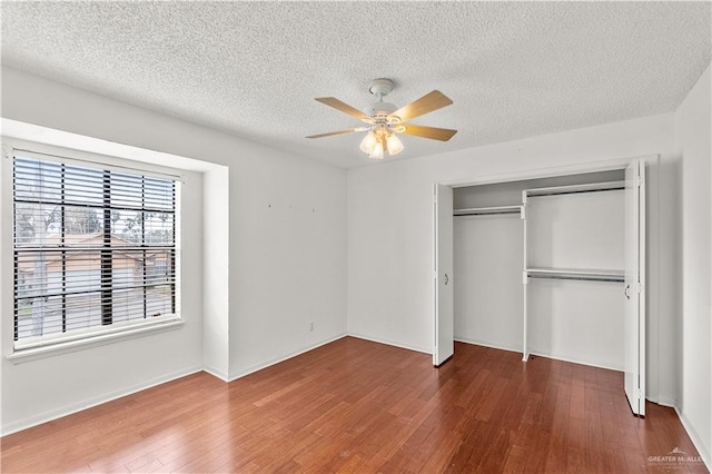 unfurnished bedroom featuring a textured ceiling, a closet, a ceiling fan, and wood finished floors