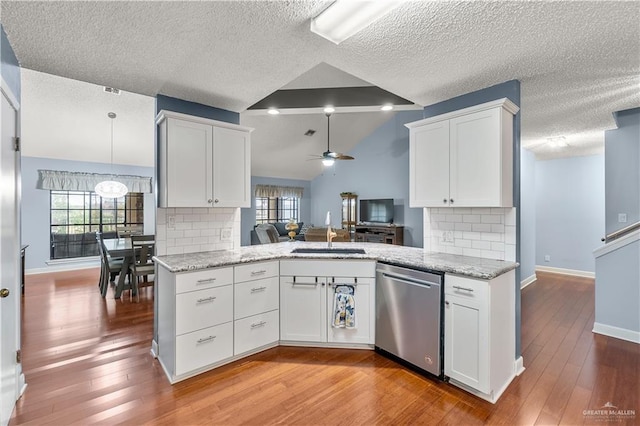 kitchen with a peninsula, a sink, white cabinets, open floor plan, and stainless steel dishwasher