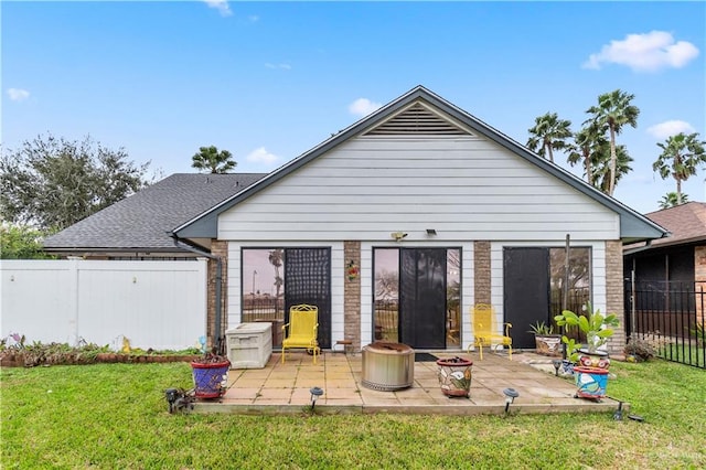 rear view of house featuring a patio area, a yard, brick siding, and fence