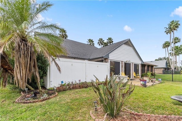 exterior space with a patio area, roof with shingles, fence, and a yard