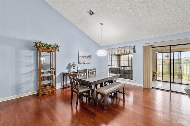 dining area featuring dark wood-style flooring, visible vents, a textured ceiling, high vaulted ceiling, and baseboards