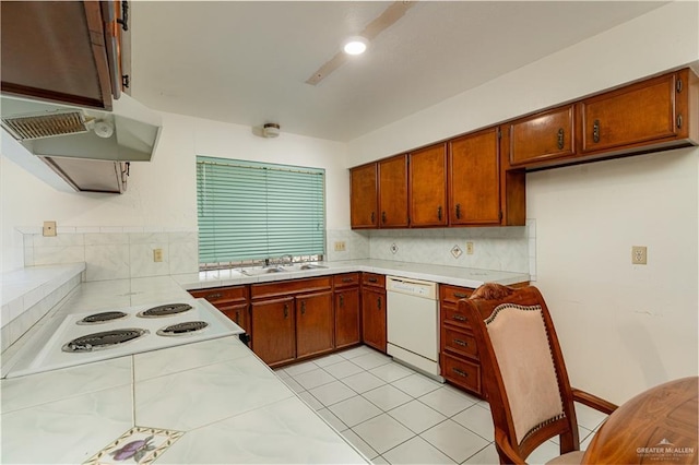 kitchen with decorative backsplash, a sink, stovetop, under cabinet range hood, and dishwasher