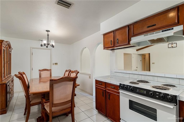 kitchen with arched walkways, visible vents, white electric range, a chandelier, and under cabinet range hood