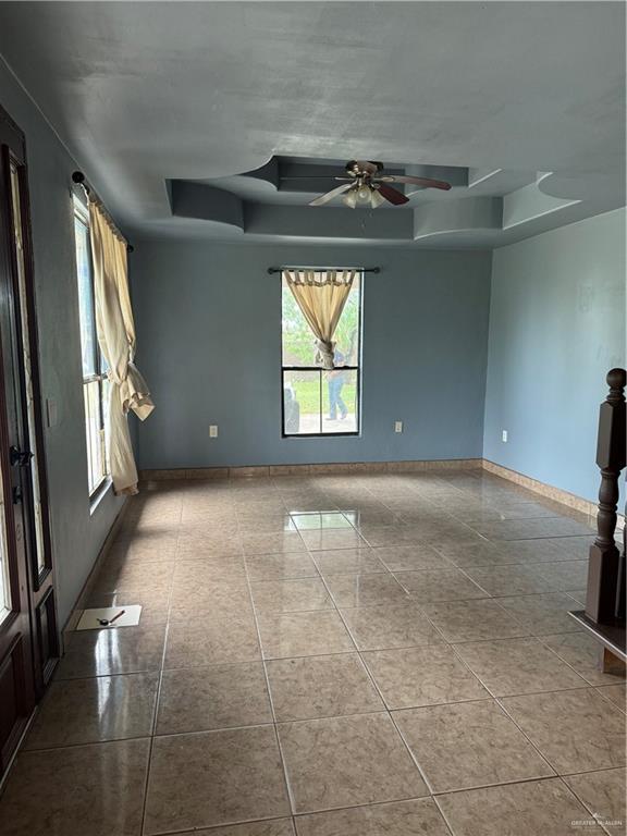 4512 Devon St, Mercedes, TX 78570 - spare room featuring a raised ceiling, baseboards, a ceiling fan, and tile patterned floors