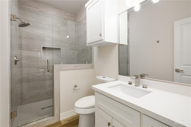 bathroom featuring vanity, a shower with shower door, and toilet