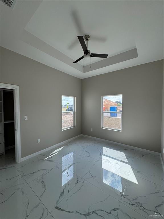 empty room featuring ceiling fan and a raised ceiling