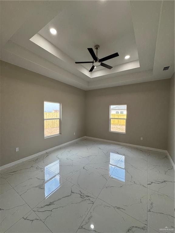 spare room with a raised ceiling and ceiling fan