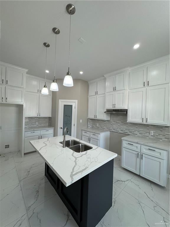 kitchen featuring an island with sink, sink, and white cabinets